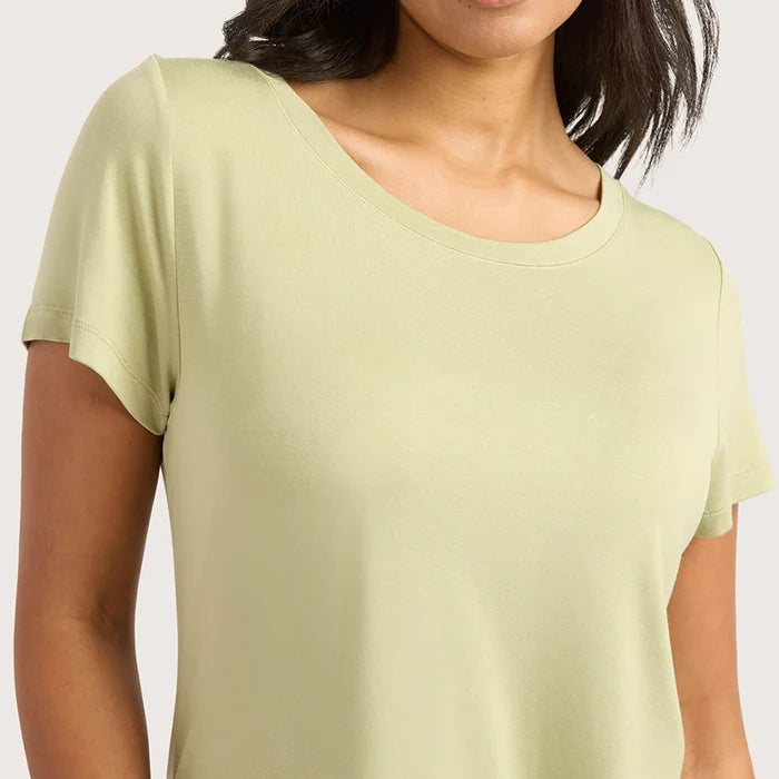 A woman wearing a pale sage green short-sleeve crewneck t-shirt, shown from the chest up against a light gray background.