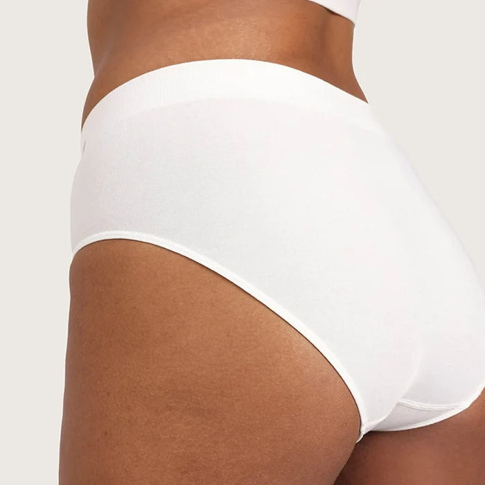 White high-waisted briefs worn by a model, shown from a side-back angle against a light beige studio background.