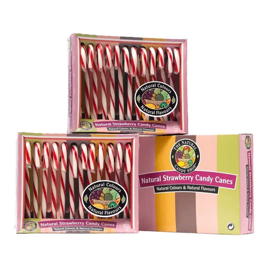 Three boxes of natural strawberry candy canes stacked together on a white background. The pink boxes contain red and white striped candy canes, and the front box features a colorful pastel design with the brand logo 'The Natural Candy Shop'.