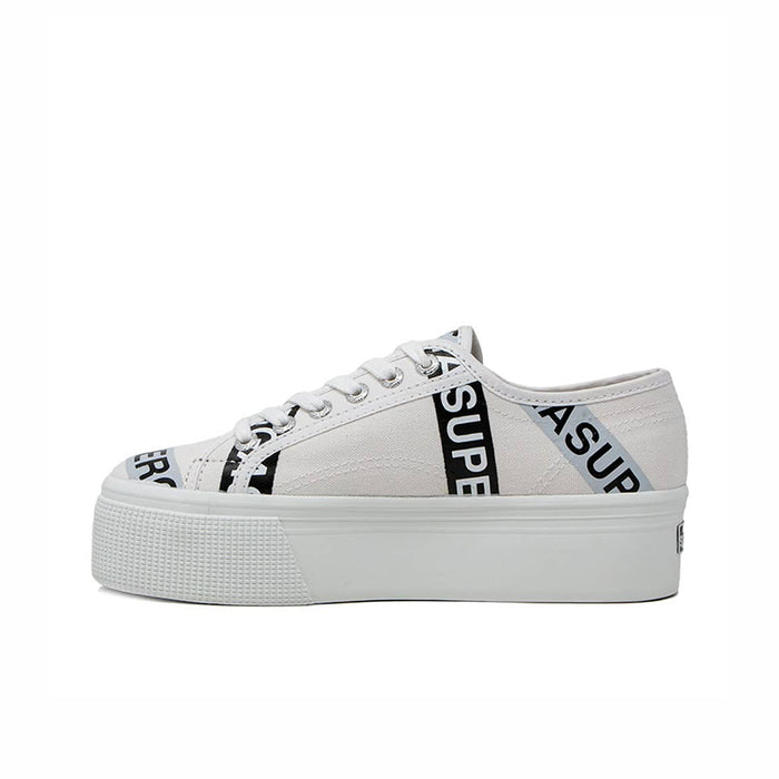 White canvas platform sneakers with lace-up front and branded side lettering tape detail